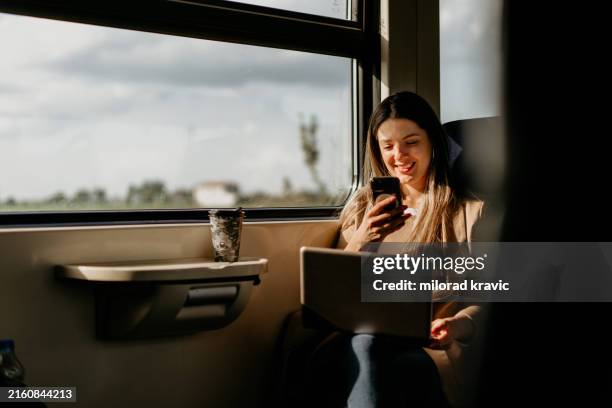 giovane donna viaggia in treno, utilizzando lap top e telefono cellulare - treno foto e immagini stock
