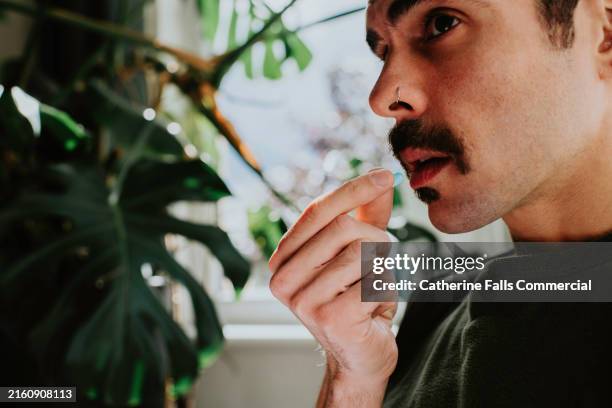 close-up of a man taking a blue pill - sida fotografías e imágenes de stock