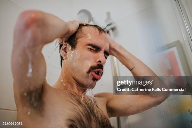 a man looks shocked as he rinses with cold water - shower stock pictures, royalty-free photos & images