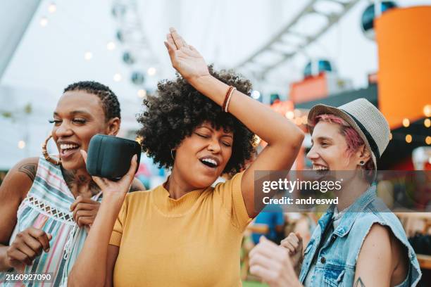 trois amis s’amusent à écouter de la musique sur le haut-parleur bluetooth - bluetooth photos et images de collection