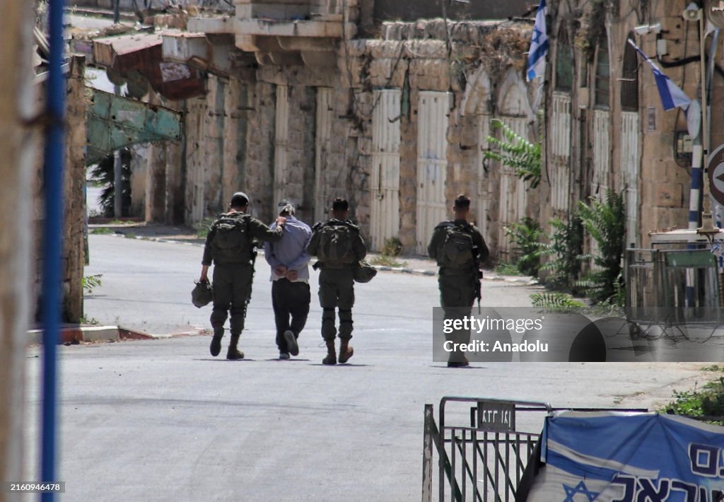 Israeli forces detain a Palestinian in the West Bank