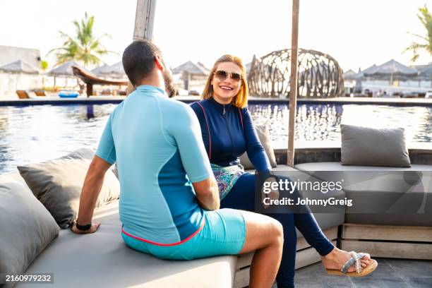 relaxed saudi couple enjoying oasis lounge at center of pool - gulf countries stock pictures, royalty-free photos & images