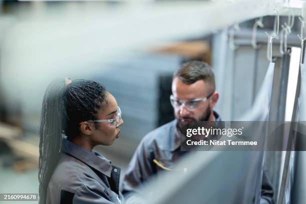 ensure continuous improvement and monitoring can increase product quality in your manufacturing process. diversity of a product development engineer team in discussing in front of engineering parts to improve the quality of the production process. - ingeniería mecánica fotografías e imágenes de stock