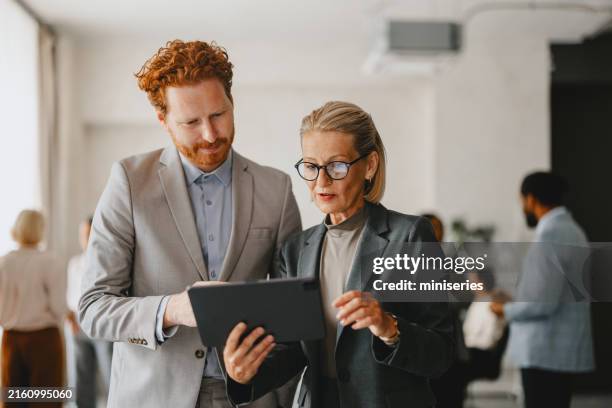 business colleagues discussing work on digital tablet in office - junior level stock pictures, royalty-free photos & images