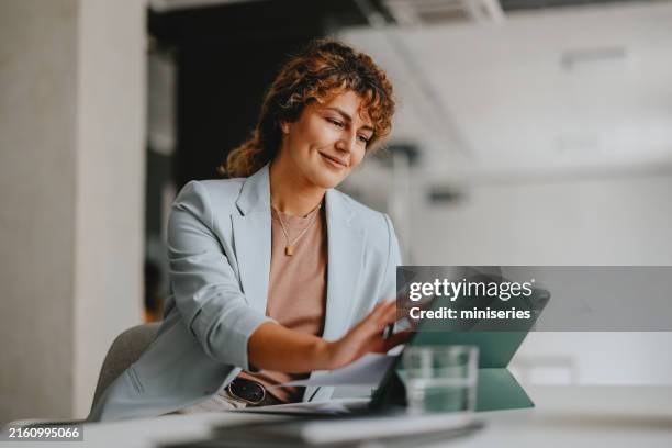 businesswoman working on tablet in modern office setting - formal dress code stockfoto's en -beelden