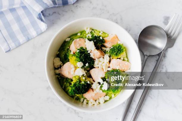 white plate with pasta risoni, salmon fillet, broccoli and cheese on white marble background. delicious balanced food concept. - zucchini noodles salmon stock pictures, royalty-free photos & images