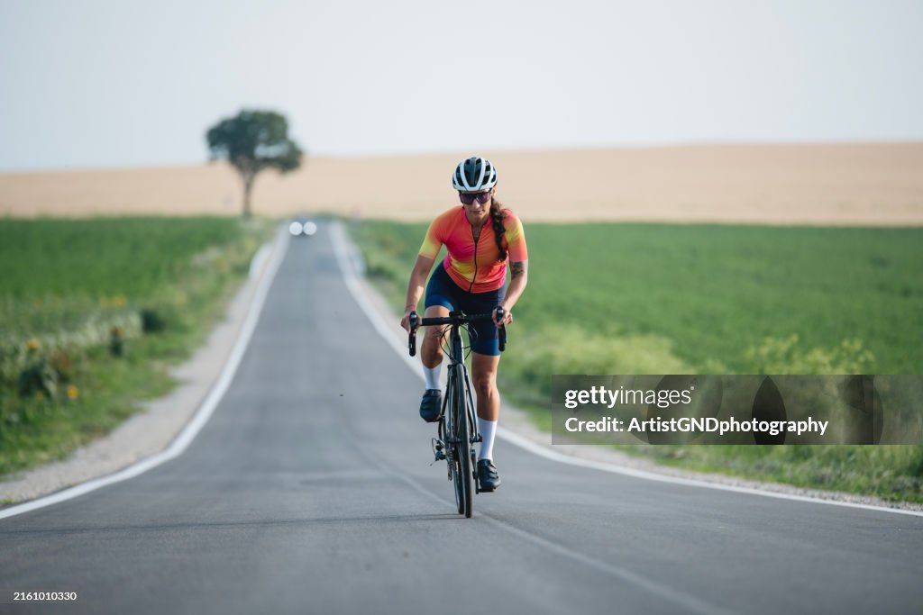 Young female is road cycling on a non urban road.
