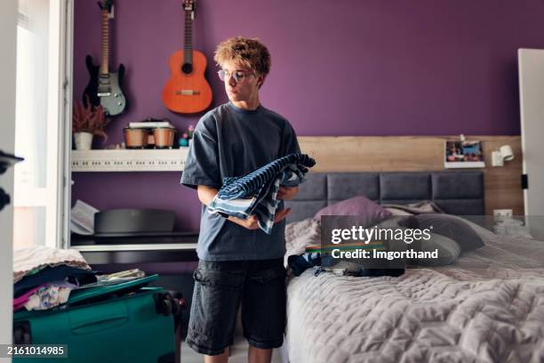 teenage boy is packing for summer vacations. - alleen tienerjongens stockfoto's en -beelden