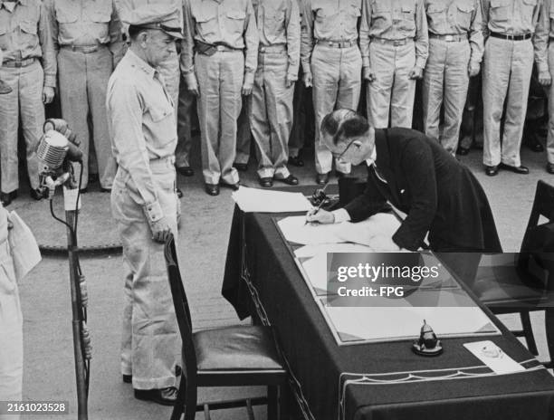 Lieutenant General Richard K Sutherland of the United States Army watches as Japanese Foreign Minister Mamoru Shigemitsu signs the Japanese...
