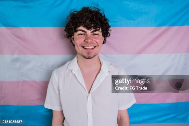 portrait of a transgender male with transgender flag in the background - transexual stock pictures, royalty-free photos & images