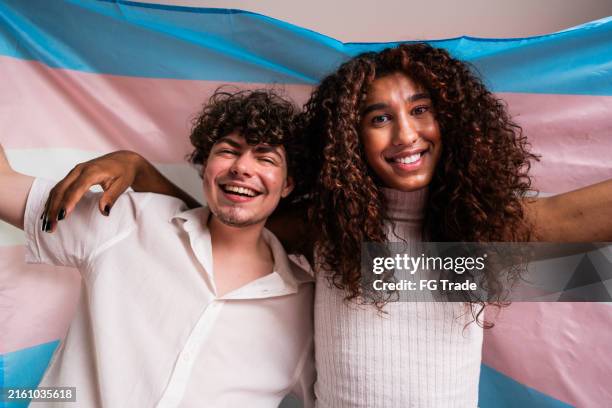 portrait of transgender friends holding transgender flag on a studio shot - transgender stockfoto's en -beelden
