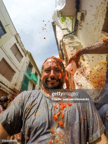 a male latin tourist enjoying in buñol, valencia, spain "la tomatina" festival. - tomato costume stock pictures, royalty-free photos & images