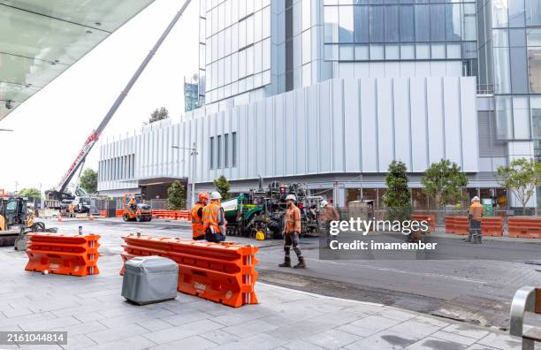 road repairs in city with construction workers and machinery, background with copy space - road construction australia stock pictures, royalty-free photos & images