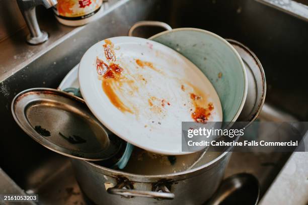 dirty dishes piled up in a commercial kitchen sink - vaisselle sale photos et images de collection