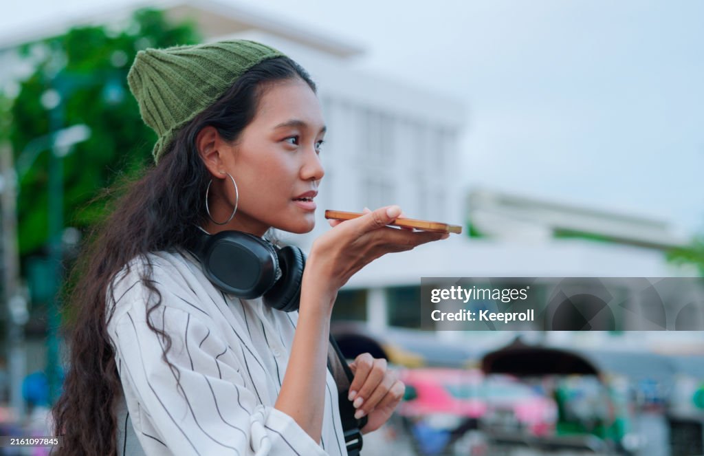 タクシーを呼ぶためにAIアプリを使用しているアジア人女性