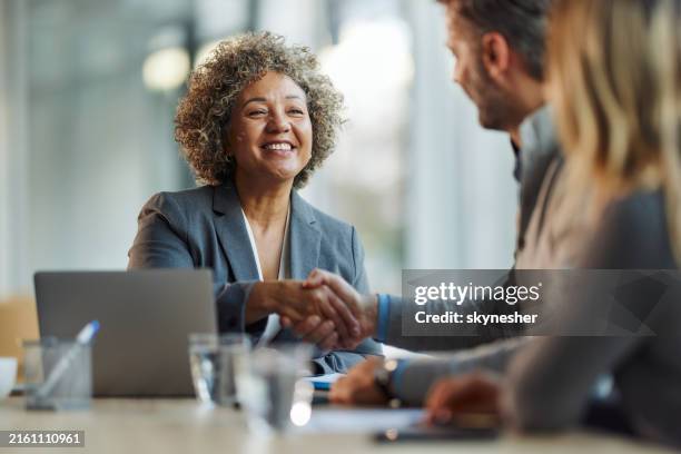 happy insurance agent shaking hands with her customers in the office. - kunde stock-fotos und bilder