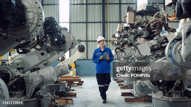 ingeniera adulta joven que trabaja con una máquina de brazos robóticos en la industria de fabricación de almacenes - humano-robot fotografías e imágenes de stock