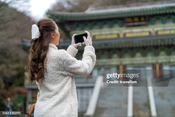 happiness asian traveller entering tongdosa temple young asian traveler traveling into jeju temple in island famous attraction, south korea - tongdosa temple stock-fotos und bilder