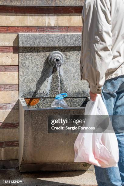 man fills up a bottle with mineral water, mineral hot water spring in sofia, bulgaria - riempire foto e immagini stock