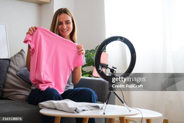 young woman is recording a video blog about fashion for her followers - blogging stock pictures, royalty-free photos & images