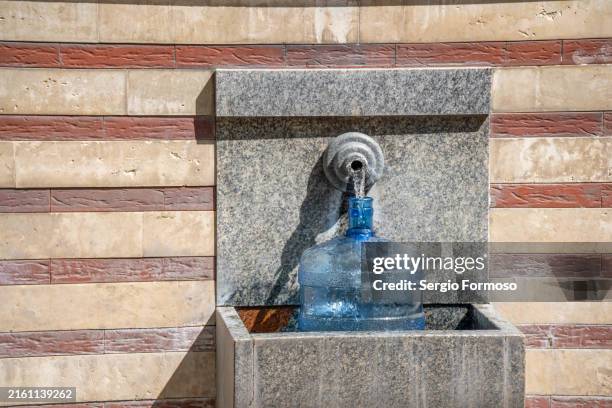 a plastic bottle being fill up with water from a natural source in sofia, bulgaria - encher atividade imagens e fotografias de stock