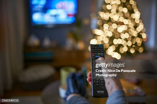 human hand pointing remote control at working television screen - man remote couch stock pictures, royalty-free photos & images