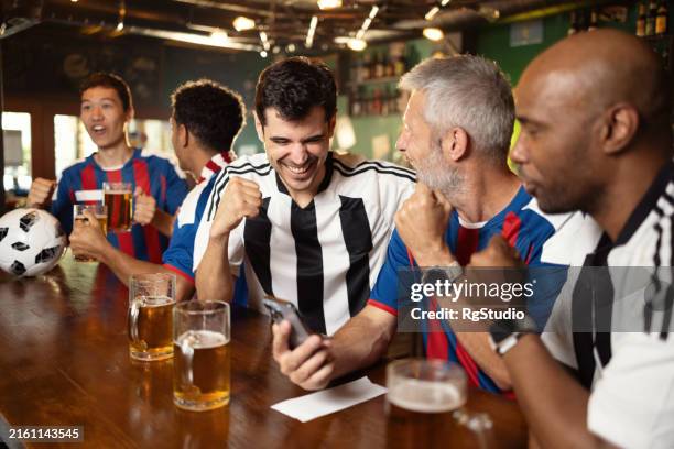los entusiastas del deporte emocionados se reunieron en el pub para el juego - apuestas deportivas fotografías e imágenes de stock
