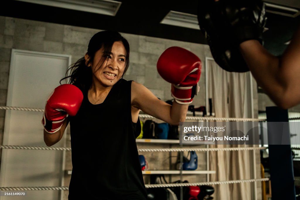 Women doing pad work training in a boxing gym.