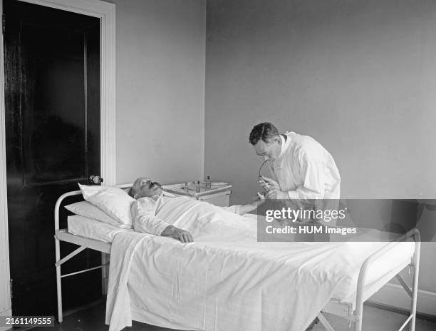 Doctor attending to a patient in a hospital ca. 1922.