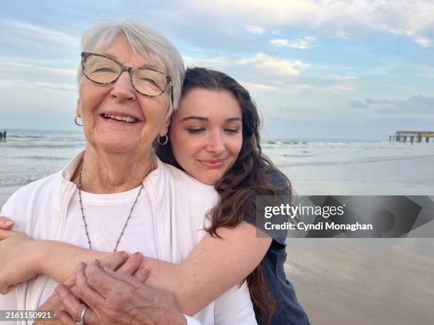 grandmother and teenager on a walk at the beach on a family weekend getaway. - grandmother stock pictures, royalty-free photos & images