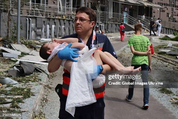 Medical worker carries in arms a child, hospital patient, amid debris in a yard of the building of one of the largest children’s hospitals of...