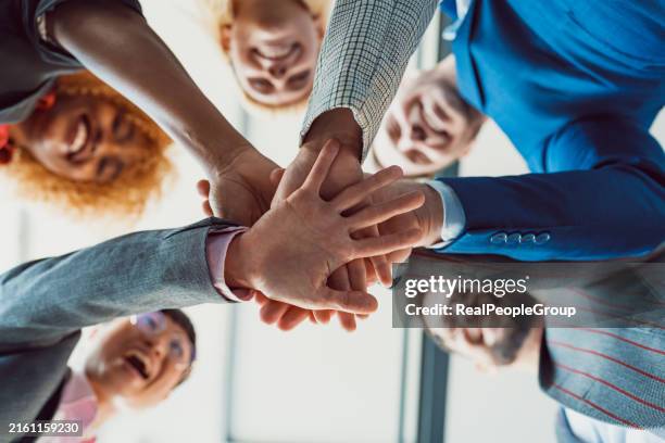 team huddle with hands stacked together in unity - lealdade imagens e fotografias de stock