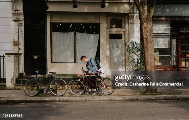 a commuter arrives at his place of work, locking up his bike at a bike rack - fahrradschloss stock-fotos und bilder