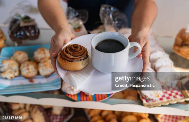 Waitress Serving A Cinnamon Bun With A Black Coffee At A Cafe, Bildbanksbilder