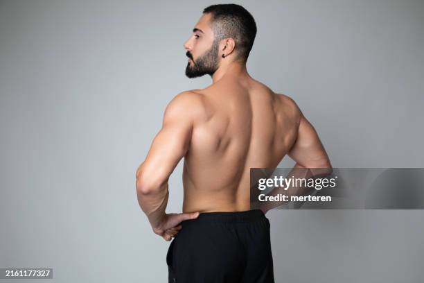 rear view of a muscular man flexing his biceps and showing off his defined back muscles, emphasizing strength and fitness. - posterior view of arm muscles stock pictures, royalty-free photos & images