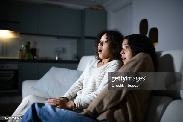 sisters watching tv on sofa: scary movie - medo imagens e fotografias de stock