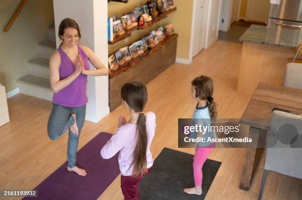 mother and daughters perform yoga - op een been staan stockfoto's en -beelden