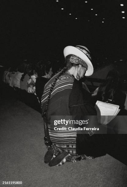 View, from behind, of an unidentified participant, in a traditional Peruvian hat and shawl, as she kneels, filling out a questionnaire during the...