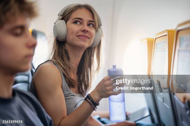 teenage girl drinking water while travelling by plane - water bottle stock pictures, royalty-free photos & images