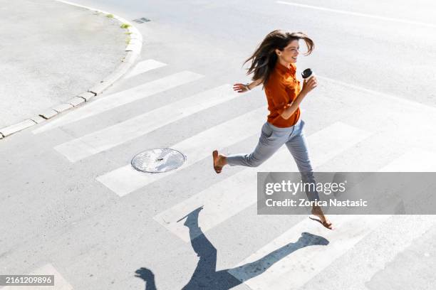 femme traversant la rue à la hâte - chaussures blanches photos et images de collection