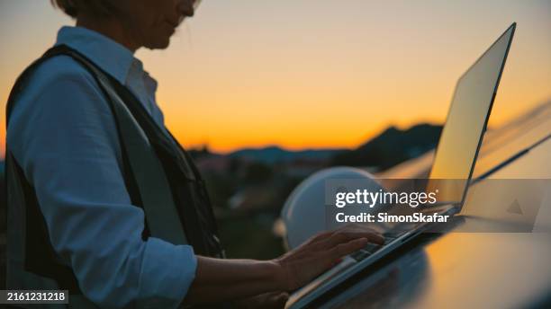 joyful female engineer with laptop at solar energy farm - koolstofvoetafdruk stockfoto's en -beelden