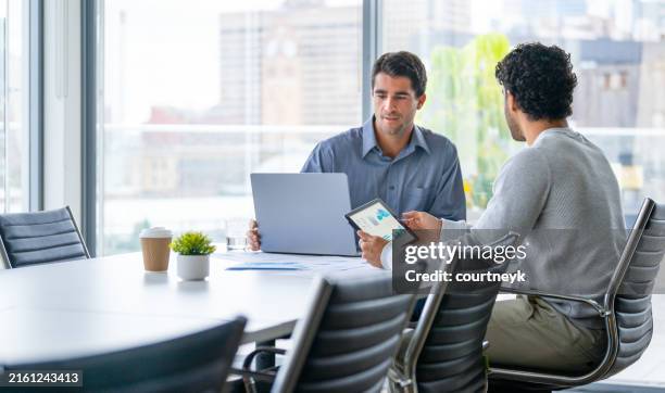 two businessmen working on a digital tablet and laptop computer in the office a board room or meeting room. - customer service man stock pictures, royalty-free photos & images