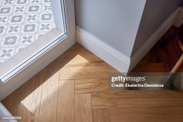 the bright corner features hardwood floor and a patterned tile entryway that create an inviting and stylish atmosphere - pavimento foto e immagini stock