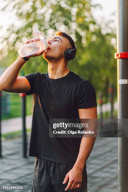 protein shake during workout. man with headset, drinking water early in the morning. - infused water stock pictures, royalty-free photos & images