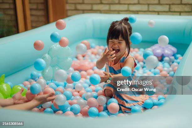 cheerful asian little girl having fun in ball pool - multi coloured people stock pictures, royalty-free photos & images
