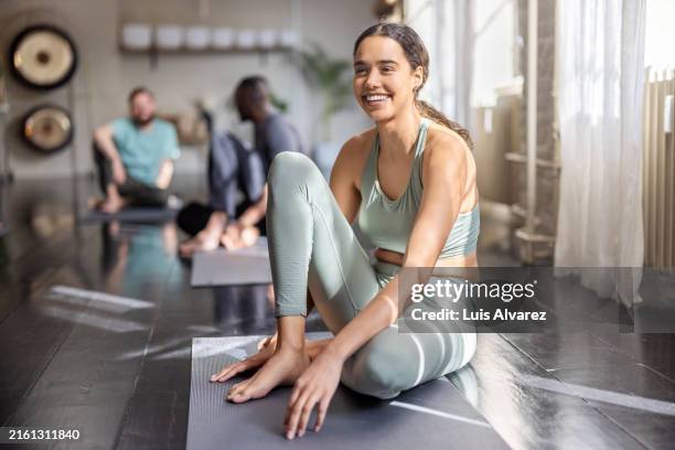 young woman smiling while resting at a yoga class - yoga studio stock pictures, royalty-free photos & images