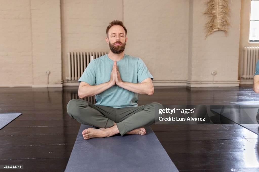 Mid adult man doing meditation in a yoga class