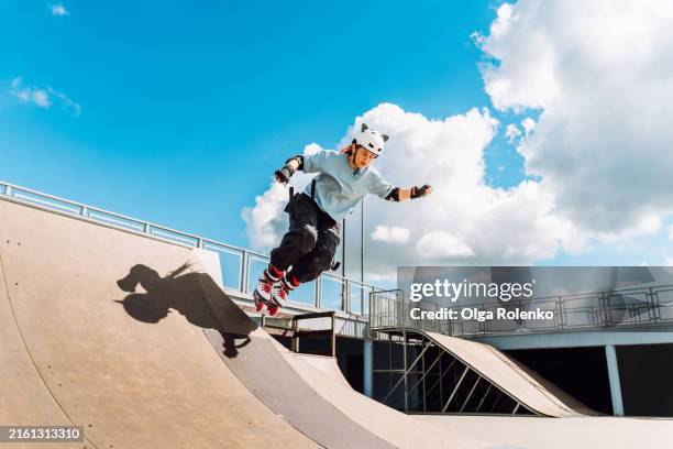 alternative life and inline skating: woman in helmet skates on pipe ramp against blue sky - halfpipe photos et images de collection