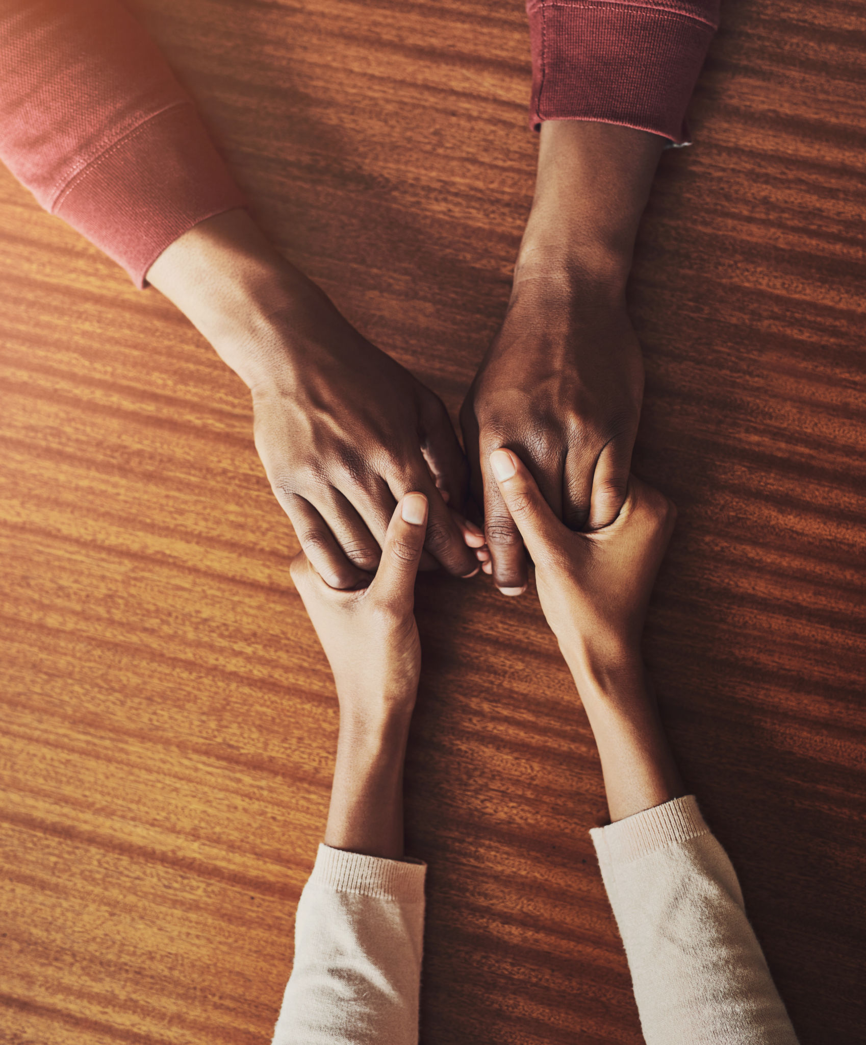 Couple, holding hands and above for support in home for care, connection and empathy for mental health. People, comfort and partner for help with kindness, bonding and solidarity for grief on table Couple, holding hands and above for support in home for care, connection and empathy for mental health. People, comfort and partner for help with kindness, bonding and solidarity for grief on table