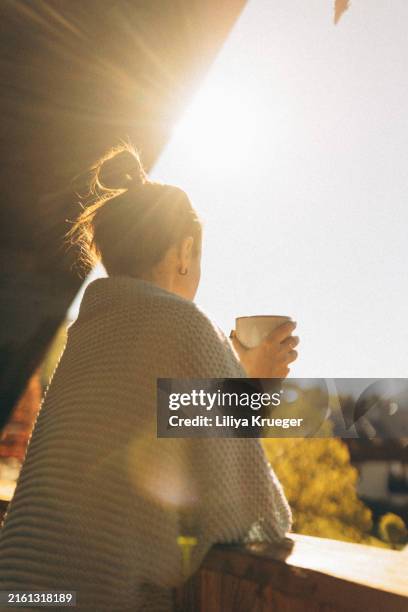 a woman enjoys her morning coffee on sunny balcony in austria. - wasserform stock-fotos und bilder